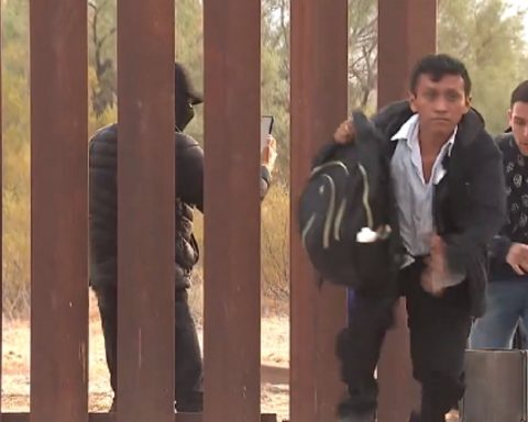 Illegal aliens pour through a breach in the border wall in Lukeville, Arizona, while a human smuggler records their faces.